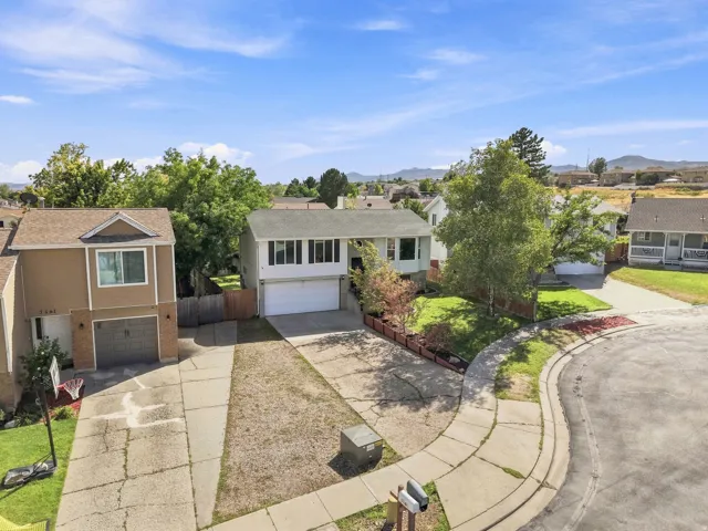 Split-level residence featuring a two-car garage, mature landscaping, and a paved driveway