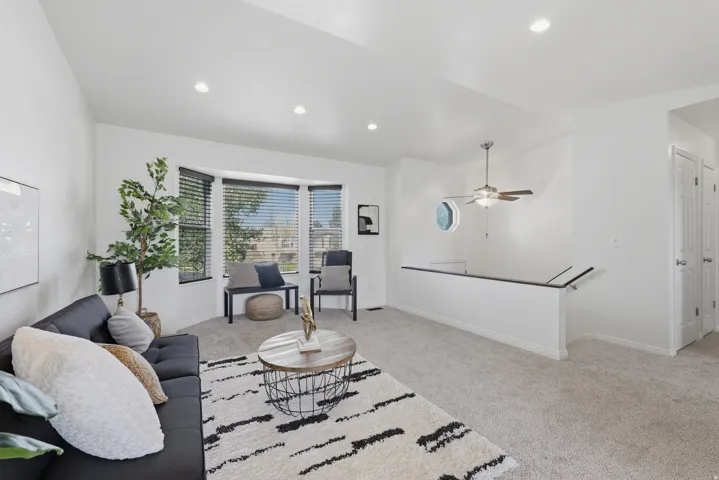 Recessed lighting, bay window, ceiling fan, and carpeted flooring with white walls