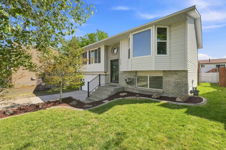 Split-level exterior featuring light-colored siding, a prominent bay window, and a concrete pathway