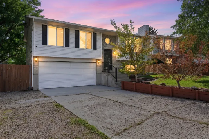 Multi-level exterior with a two-car garage, white siding, and brick accents