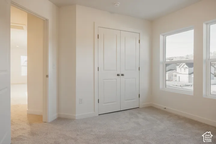 Bedroom 3 - Neutral wall paint, light-toned carpet flooring, dual pane windows, and a built-in closet with double doors