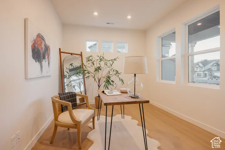 Recessed ceiling lighting, multiple large windows, additional transom windows, light wood-finish flooring, and white painted walls