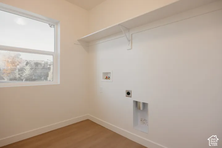Laundry area featuring a single window, a built-in white shelf, and wood-finish flooring