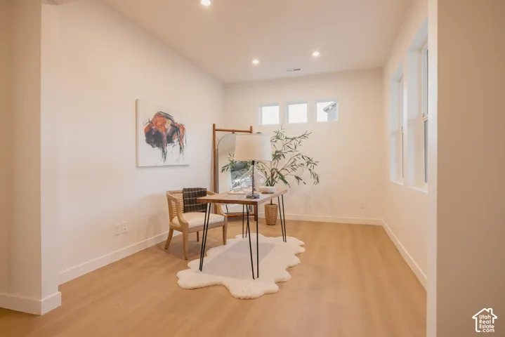 Neutral wall paint, recessed lighting, wood-finish flooring, and multiple windows