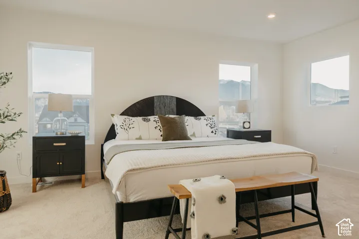 Primary Bedroom. Plush carpeting, recessed lighting, multiple windows, and a built-in headboard