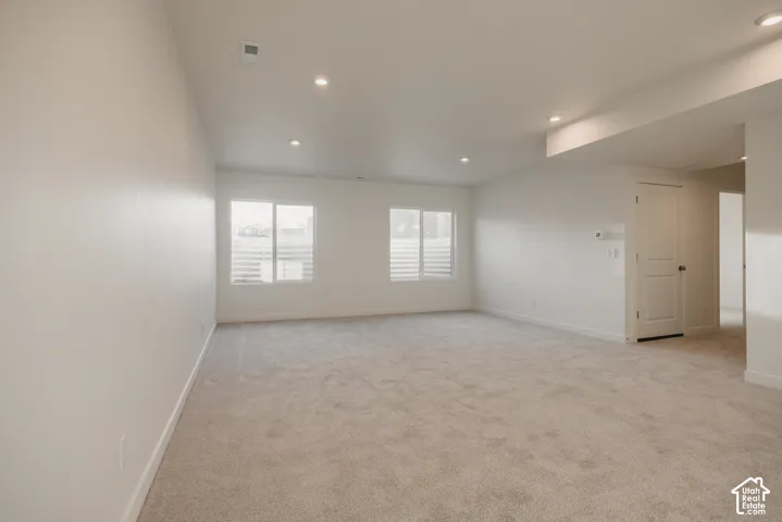 Huge basement living room - Spacious room with recessed lighting, two windows, and light-colored carpeting