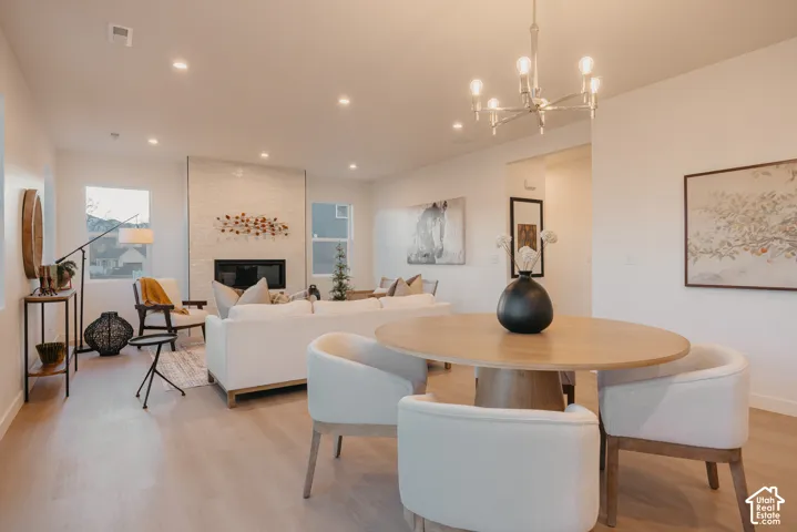 Open-concept living area with light wood-finish flooring, recessed lighting, and a chandelier