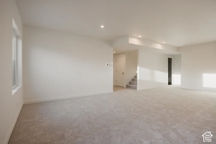 Huge basement living room - Expansive room featuring light-colored carpeting, recessed lighting, a window, and access to a staircase