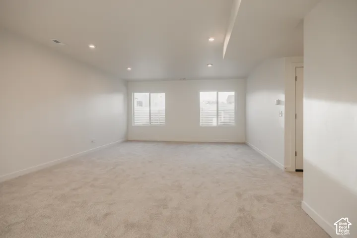 Huge basement living room - Recessed lighting, light-colored carpeting, two windows with horizontal blinds, and a white interior door