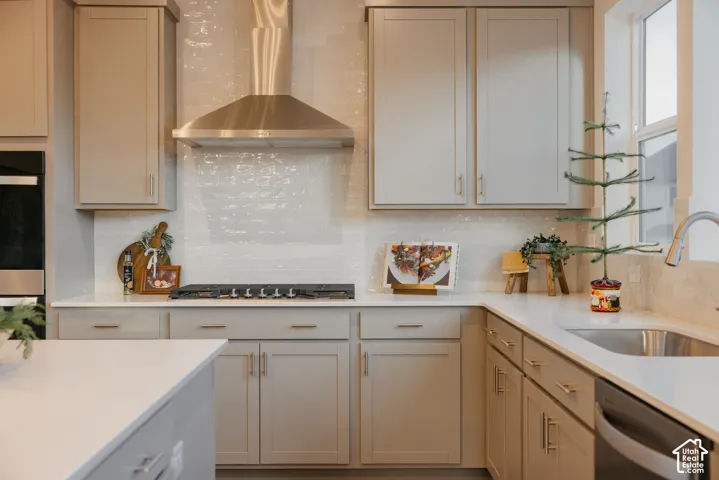 Kitchen featuring light gray cabinetry, white countertops, stainless steel appliances, a gas cooktop, and a textured tile backsplash