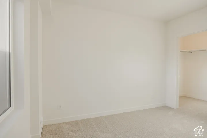 Bedroom 4 - Light-colored carpeting with a window and a closet featuring a single hanging rod and shelf