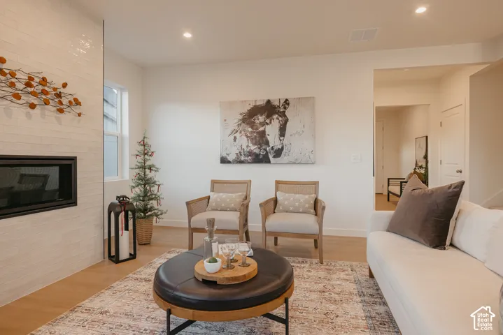 Living area featuring a floor-to-ceiling fireplace with a tiled surround, recessed lighting, and wood-finish flooring
