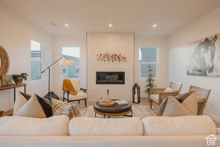 Recessed lighting, wood-finish flooring, and a tiled fireplace with a built-in firebox create a refined atmosphere