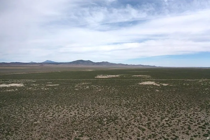 Expansive desert landscape with distant mountain ranges under a vast sky