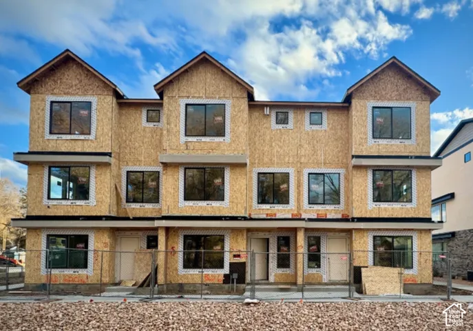 Multi-level construction with multiple window openings, prominent gabled rooflines, and a uniform exterior sheathing