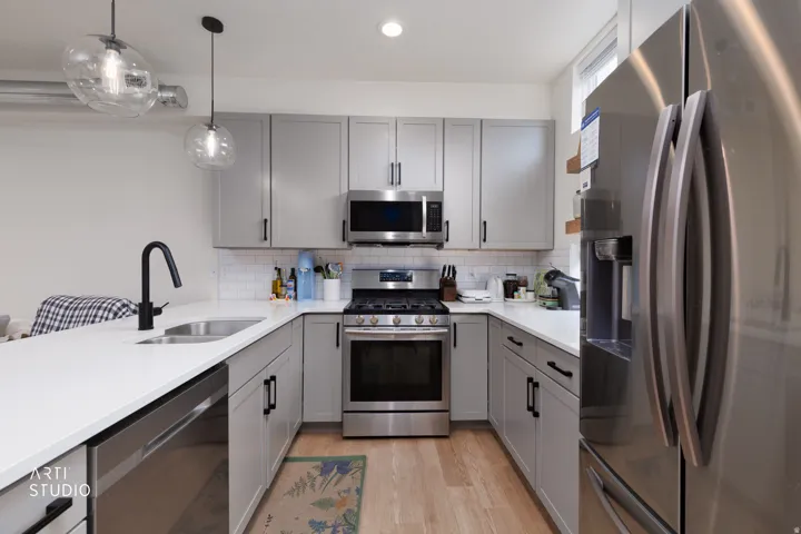 Contemporary kitchen featuring grey cabinetry, stainless steel appliances, white countertops, and a subway tile backsplash