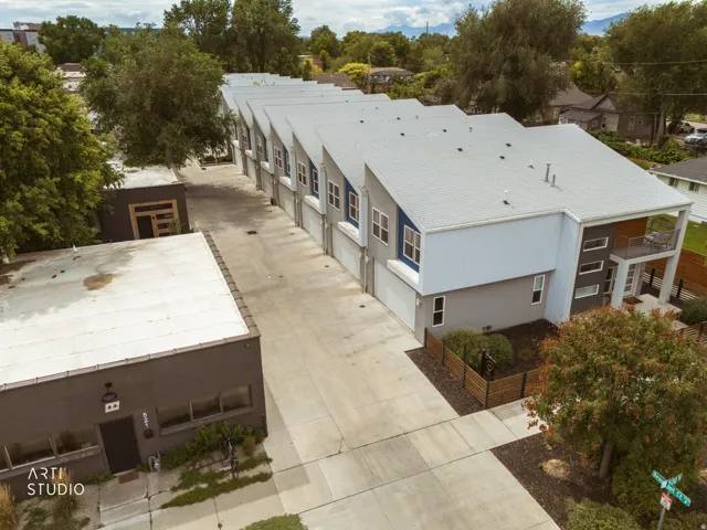 Modern townhome exterior with a private balcony, integrated garage, and a contemporary flat roof design
