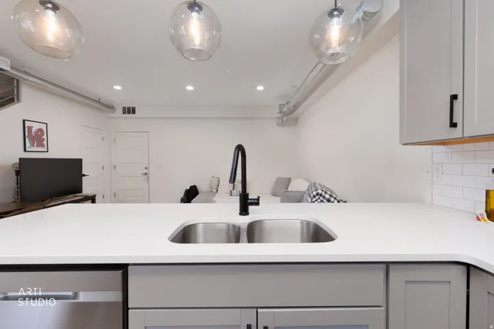White countertops with an undermount double-basin sink and a matte black gooseneck faucet
