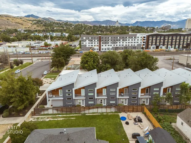 Contemporary townhome row with angled rooflines, dark grey and wood-panel facades, multiple balconies, and multiple window configurations