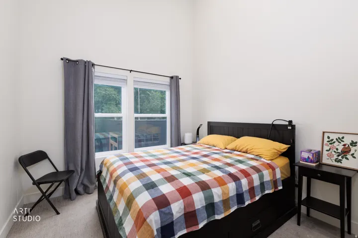 Dual windows with blinds, gray curtain panels, light gray carpet flooring, and white wall finishes