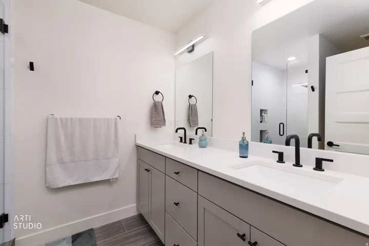 Dual vanity with integrated sinks, matte black fixtures, and light grey cabinetry