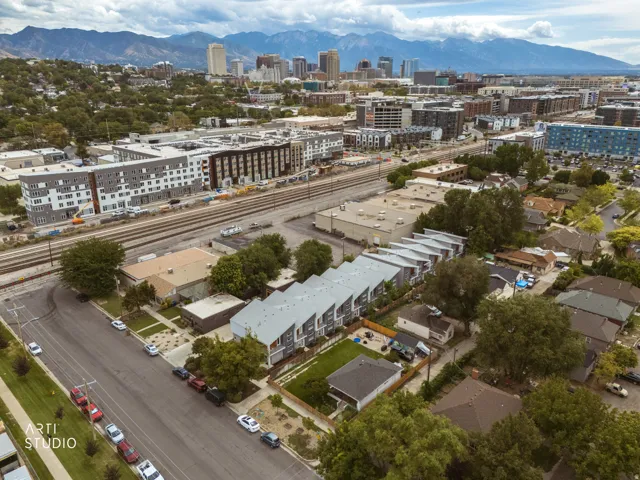 Urban setting featuring diverse architectural styles, visible railroad tracks, and distant mountain range