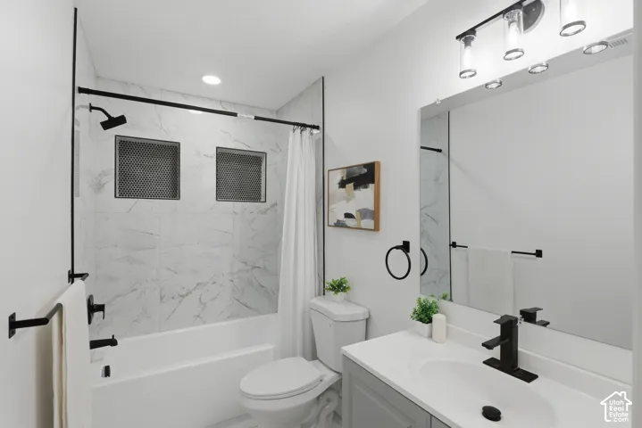 Bathroom featuring a white bathtub with tile surround, recessed shower niches, a single vanity with a white countertop and undermount sink, and matte black fixtures