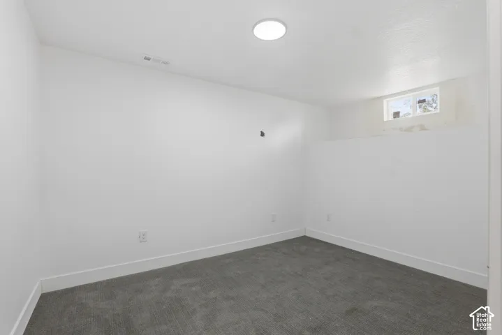 Neutral wall finishes, recessed ceiling lighting, gray carpet flooring, and a single window