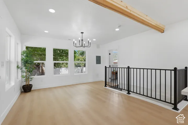 Recessed lighting, exposed wood beam, wood-finish flooring, contemporary chandelier, and black metal railing
