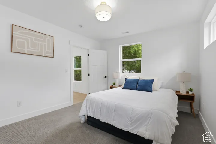 White walls, recessed window, high ceiling, gray carpeting, and a modern light fixture