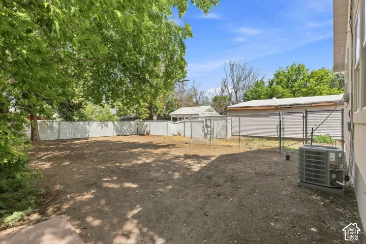 Expansive outdoor space featuring mature trees, a privacy fence, and a chain-link fence with gate