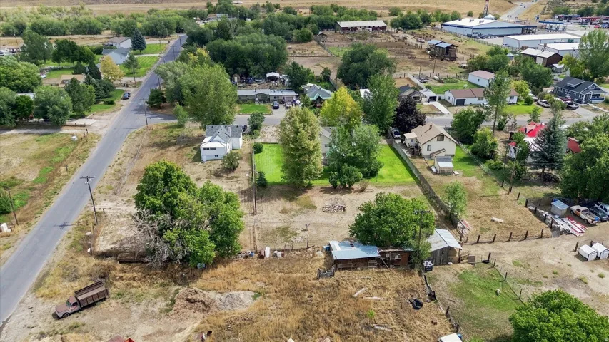 Expansive property featuring multiple structures, mature trees, and a paved road frontage