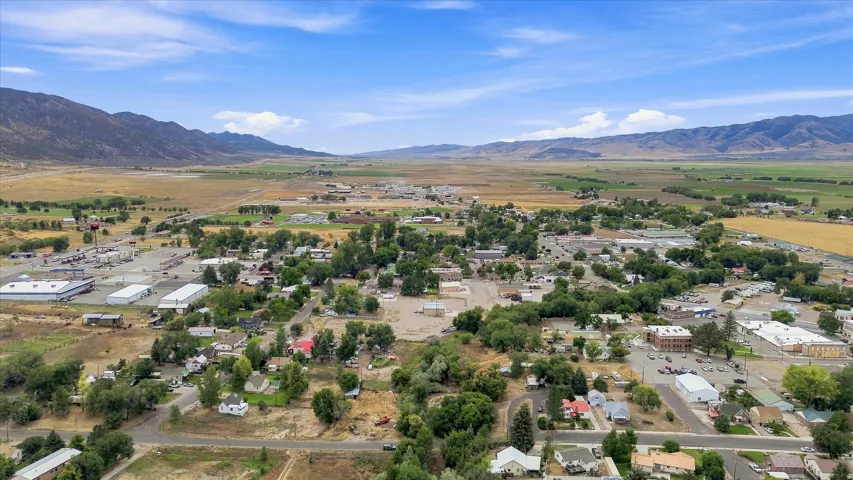 Expansive rural community with a mix of residential and commercial structures, surrounded by open fields and distant mountains