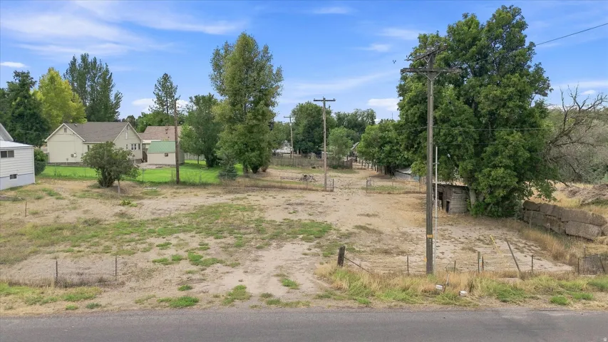 Expansive undeveloped lot with partial fencing and mature trees