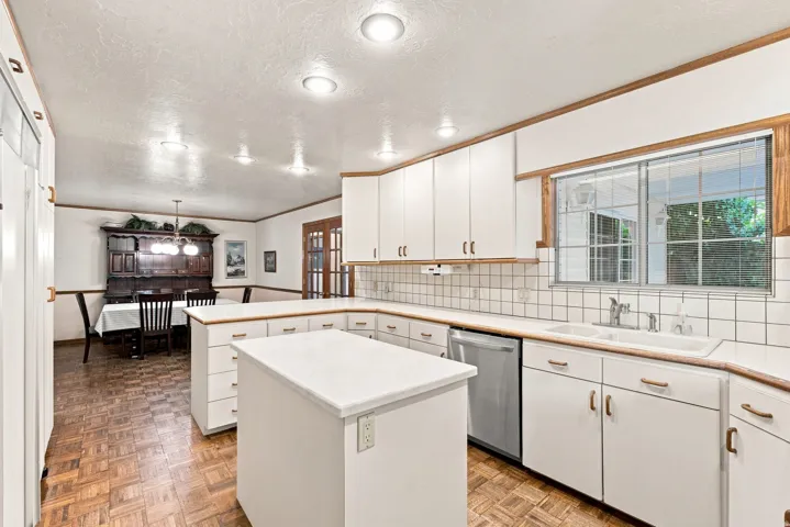 Kitchen featuring white cabinetry, a central island, a double basin sink, and a stainless steel dishwasher