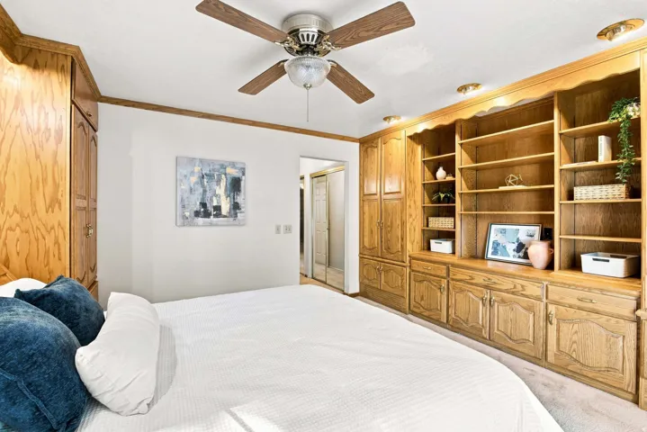 Built-in wood cabinetry with shelving and integrated storage, ceiling fan with light fixture, recessed lighting, and wall-to-wall carpeting