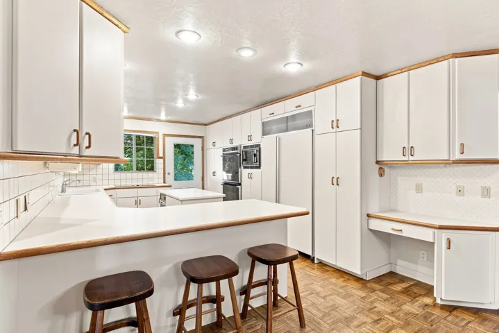 Spacious kitchen featuring white cabinetry, a built-in oven, recessed lighting, and wood-finish flooring