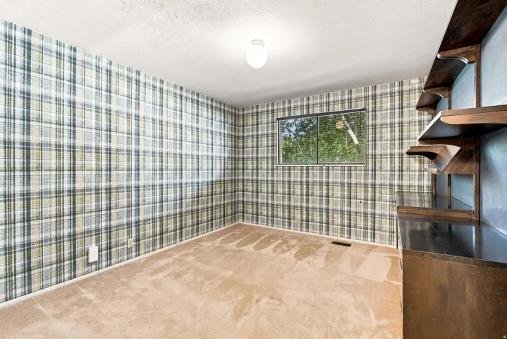 Wall-to-wall carpeting, built-in shelving, window with exterior exposure, overhead lighting, and patterned wallpaper