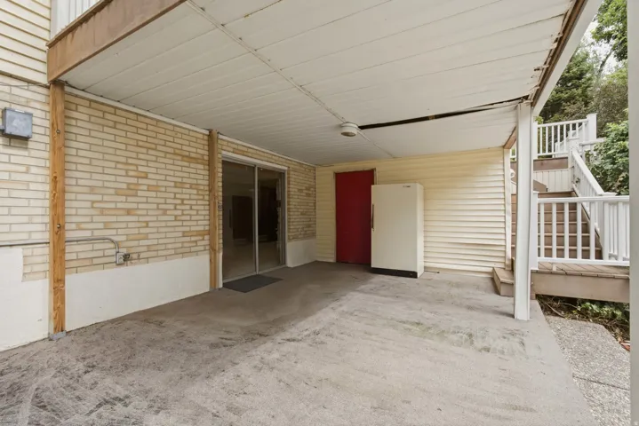 Covered patio with a concrete surface, brick wall, and sliding glass door access