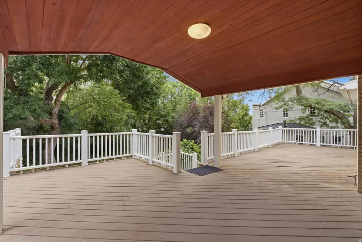 Expansive outdoor deck featuring wood-finish flooring and white railings