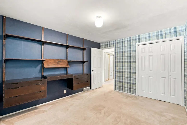 Built-in shelving and desk unit, carpeted flooring, bi-fold closet doors, and interior paneled doors