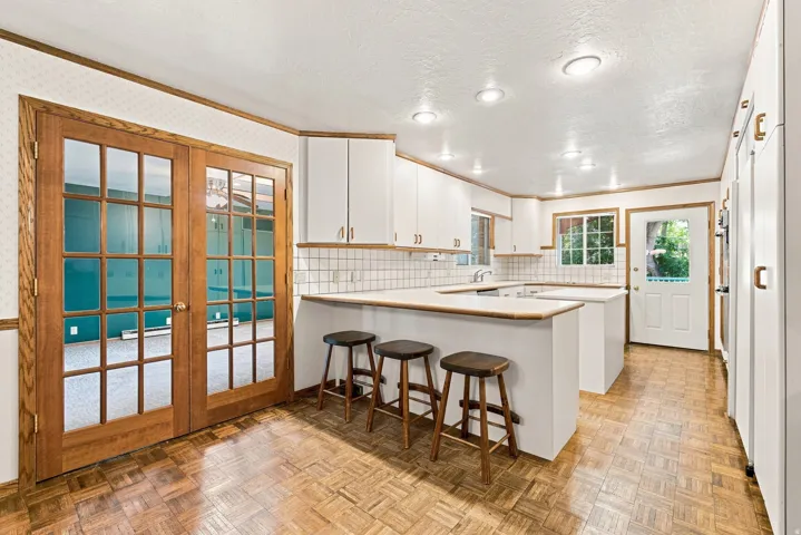 Kitchen featuring white cabinetry, tile backsplash, wood-finish flooring, recessed lighting, and a breakfast bar