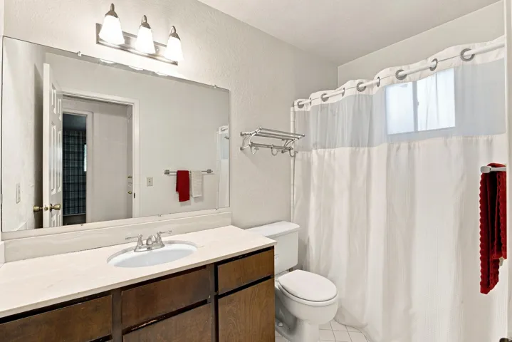Vanity with integrated sink, wood-finish cabinetry, and an expansive mirror