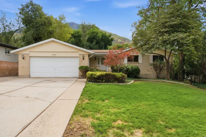 Brick exterior with a prominent two-car garage, concrete driveway, and a landscaped front yard