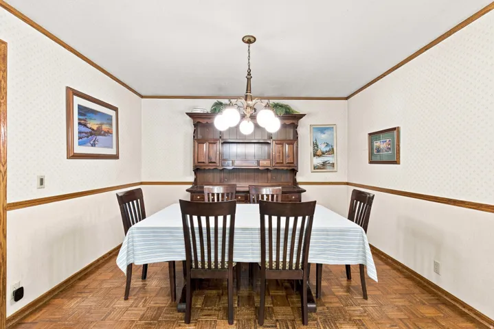 Wood-finish parquet flooring, wainscoting, decorative wallpaper, and crown molding
