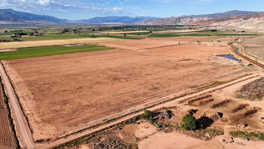 Expansive land parcel featuring a dirt road, irrigation ditch, and varied topography