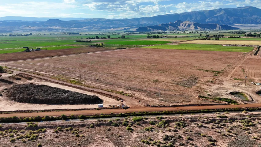 Expansive land parcel with graded access roads, a small pond, and distant mountain backdrops