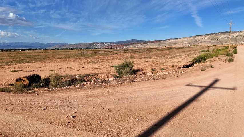 Expansive land with a dirt road, distant mountains, and a clear sky