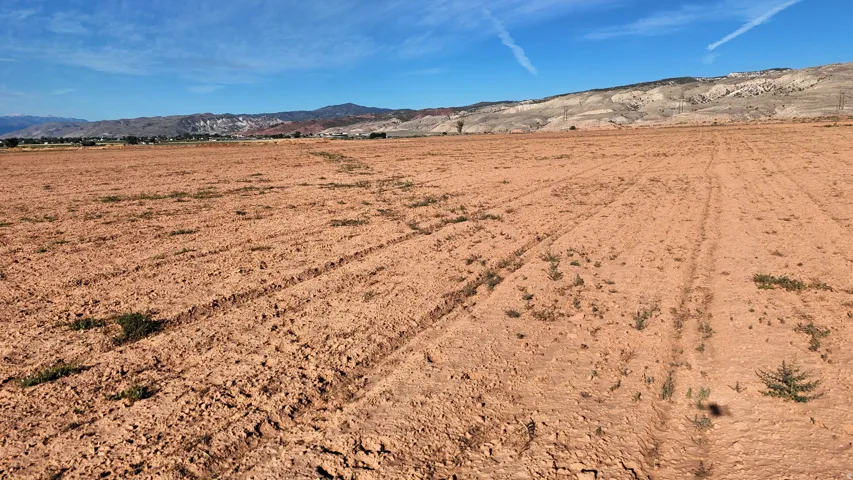 Expansive land parcel featuring tilled earth and distant mountainous terrain