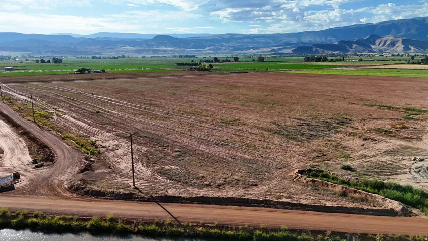 Expansive cleared land with surrounding green fields and distant mountains